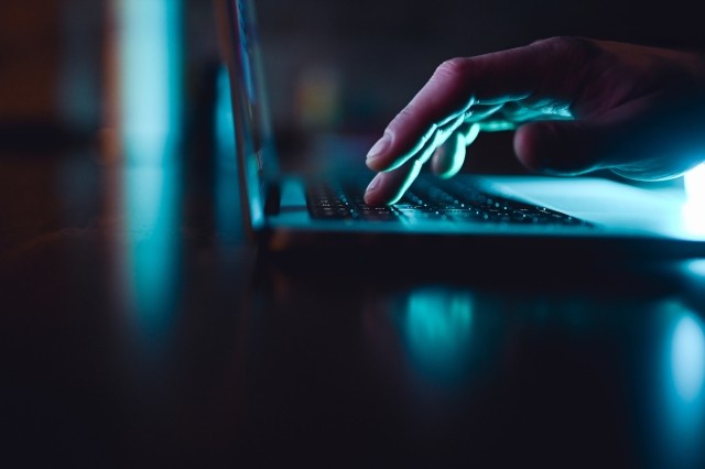 Person typing on laptop in a dark room