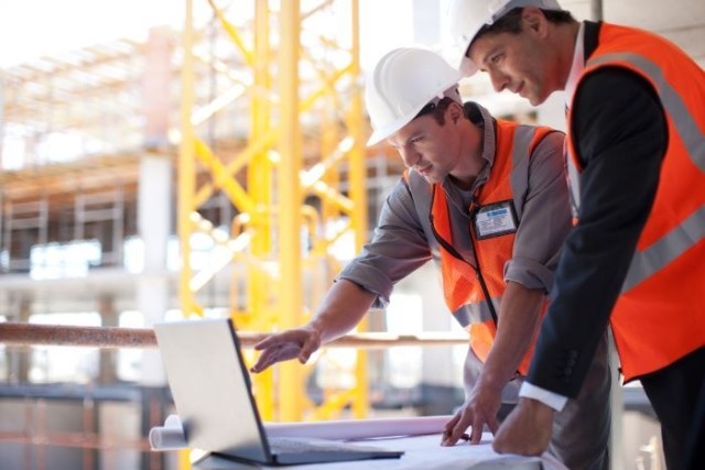men in hardhats looking at laptop
